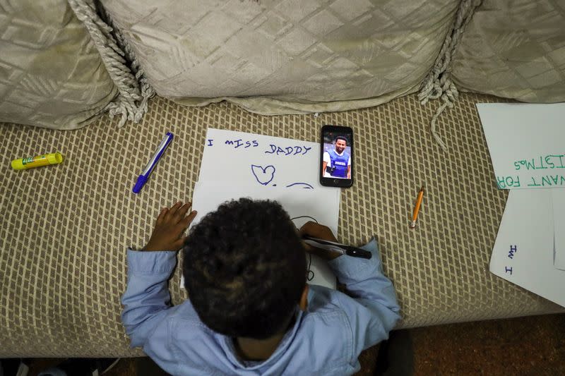 Son of Reuters cameraman Kumerra Gemechu writes a letter to his father whose picture is seen on a cell phone screen, in Addis Ababa