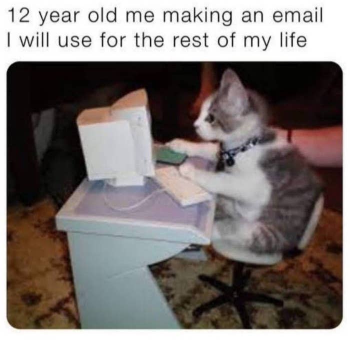 A kitten sits at a miniature desk with a tiny computer, with text above that reads: "12 year old me making an email I will use for the rest of my life."