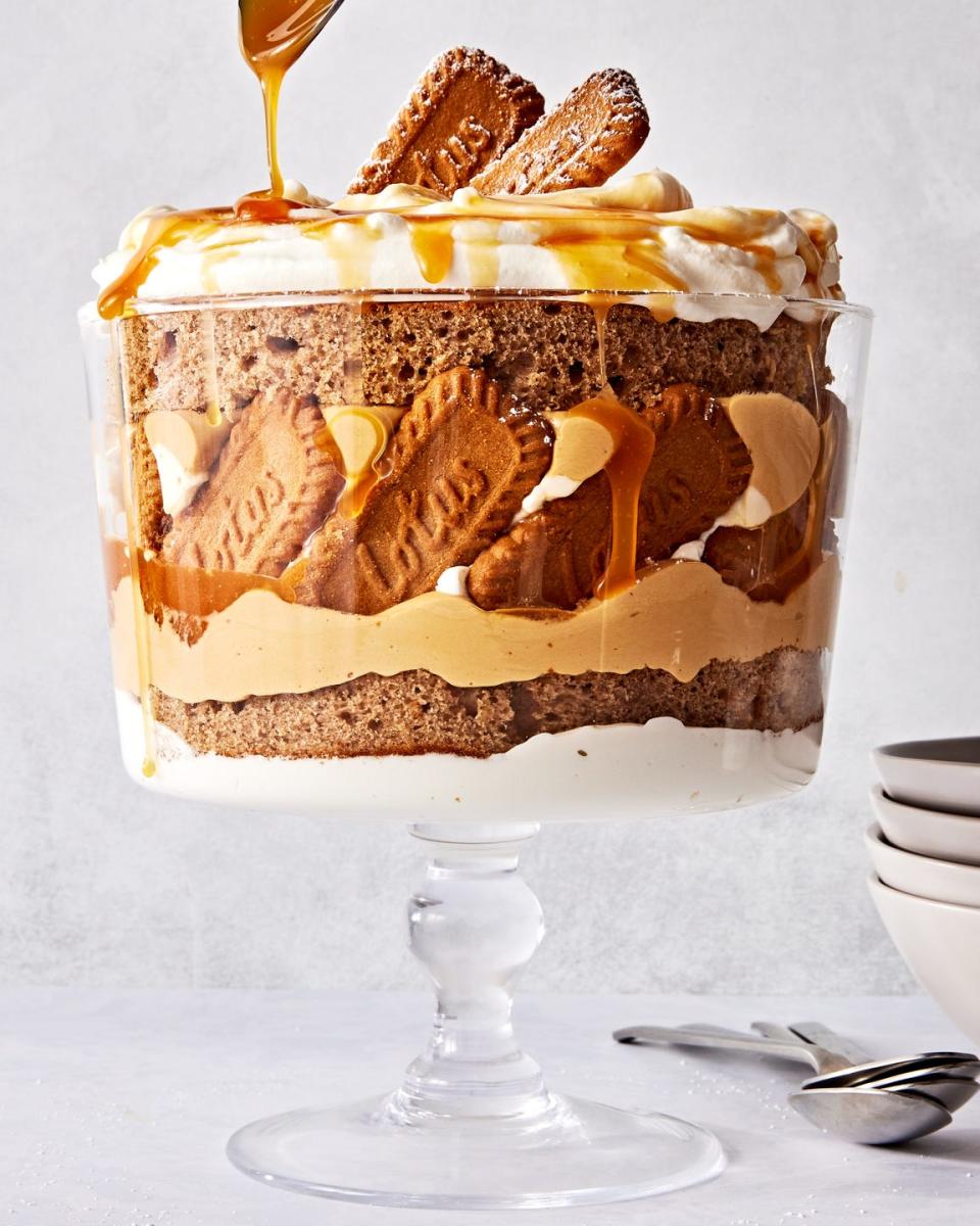 a trifle dish filled with layers of spice cake, caramel, cookie butter mousse, whipped cream, and biscoff cookies