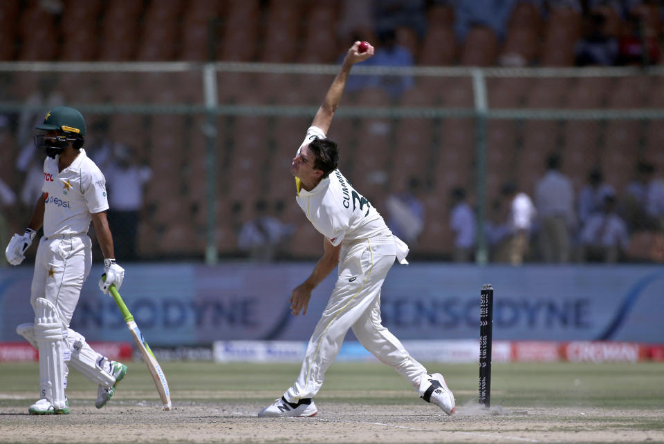 Australia's Pat Cummins, center, bowls while Pakistan's Fawad Alam watches on the fifth day of the second test match between Pakistan and Australia at the National Stadium in Karachi Pakistan, Wednesday, March 16, 2022. (AP Photo/Fareed Khan)