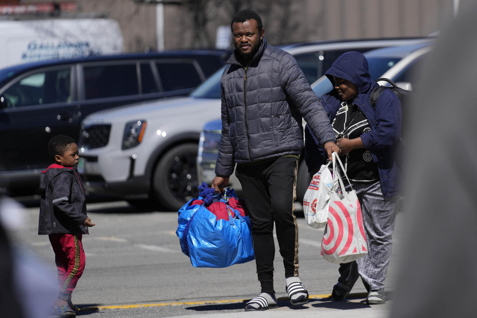 Asylum seekers arrive with their belongings at the Portland Expo Center, Monday, April 10, 2023, in Portland, Maine. The state is reopening a basketball arena for immigrants following the arrival of more than 800 asylums seekers since the beginning of the year. (AP Photo/Robert F. Bukaty)