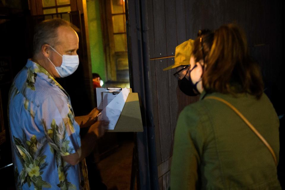 Co-owner Jonathan Katz talks to new members about a membership form outside Risky Business, that was once The Other Door but closed during the Covid-19 pandemic in the North Hollywood neighborhood of Los Angeles, California on May 21, 2021. - In order to go inside Risky Business, members must present their original vaccination card after being fully vaccinated, paying a small membership fee, signing a risk release form with penalties for lying, and waiting a full two weeks after competing their shots. While the policy is strict, once inside customers can enjoy an experience knowing that everyone else has been 100-percent vaccinated with an lively pre-pandemic atmosphere with people up close and personal - talking, hugging, playing pool and drinking without rules for masks or social distancing. (Photo by Patrick T. FALLON / AFP) (Photo by PATRICK T. FALLON/AFP via Getty Images)