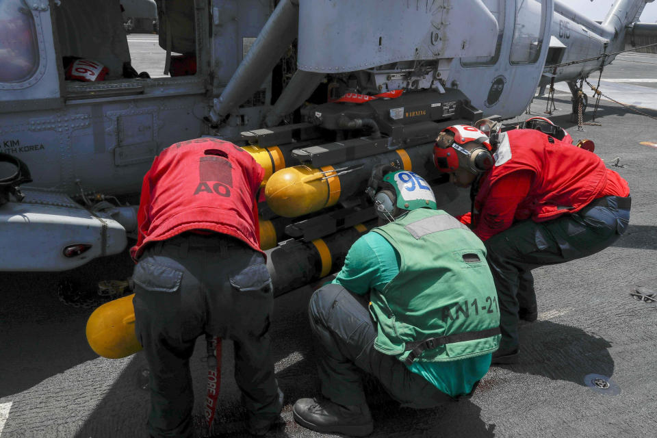 In this Wednesday, May 15, 2019, photo released by the U.S. Navy, Aviation Ordnanceman Airman Tyrik Williams, right, Aviation Electrician's Mate 2nd Class Nathan Hernandez, middle, and Aviation Ordnanceman 2nd Class Kristina Thompson, left, load an AGM-114 Hellfire missile onto an MH-60S Seahawk helicopter on board the USS Abraham Lincoln. U.S. diplomats warned Saturday, May 18, 2019, that commercial airliners flying over the wider Persian Gulf faced a risk of being "misidentified" amid heightened tensions between the U.S. and Iran. (Mass Communication Specialist Seaman Michael Singley, U.S. Navy via AP)