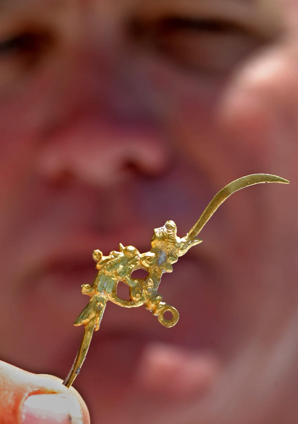 In this photo released by the Florida Keys News Bureau, Blue Water Ventures salvage company captain Dan Porter displays a tiny solid gold combination toothpick and earwax scoop Monday, May 19, 2008, in Key West, Fla. A diver on Porter's salvage boat recovered the artifact Sunday, May 18, about 40 miles west of Key West during a search for remains of the Spanish galleon Santa Margarita that shipwrecked in a 1622 hurricane. According to archaeologists, the 3-inch-long, 17th century grooming tool is more than 385 years old and was probably worn on a gold chain. Estimated value could exceed $100,000. (AP Photo/Florida Keys News Bureau, Bob Care)
