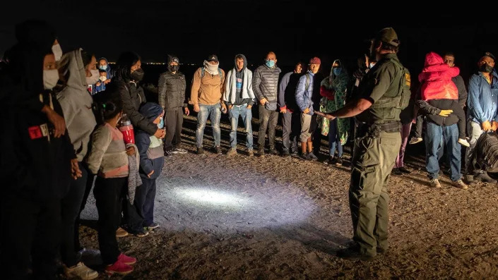 A U.S. Border Patrol agent speaks with immigrants before transporting some of them to a processing center on Dec. 9, 2021, in Yuma, Arizona. <span class="copyright">Photo by John Moore/Getty Images</span>