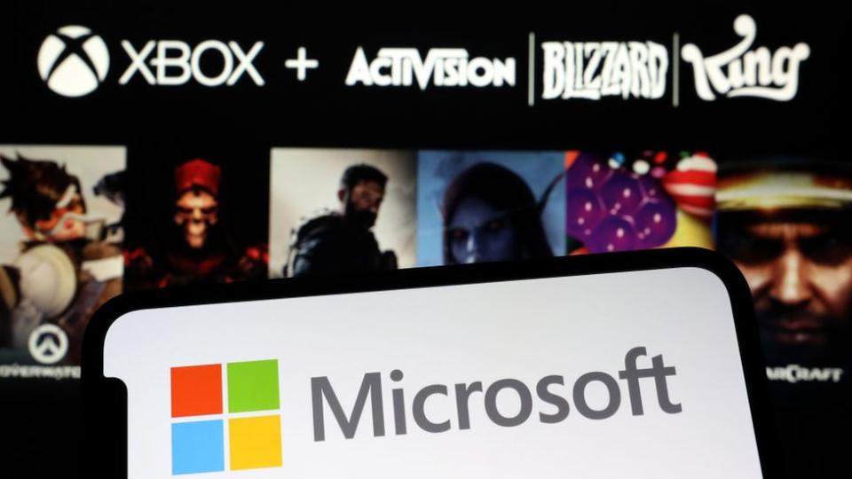 Akıllı telefon, boş bir ekranda şirket adının karşısında kırmızı, yeşil, sarı ve mavi bir kareden oluşan Microsoft logosunu görüntüler.  Arka plan bulanık ama iyi bilinen Blizzard ve Activision oyunlarından karakterlerin ana hatları görülebiliyor.  Üstlerinde Xbox, Activision, Blizzard ve King logoları var.
