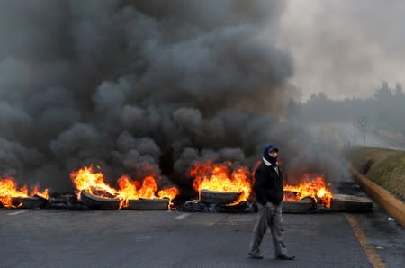 A demonstrator walks in front of a burning barricade during protests after Ecuador's President Lenin Moreno's government ended four-decade-old fuel subsidies, near Machachi