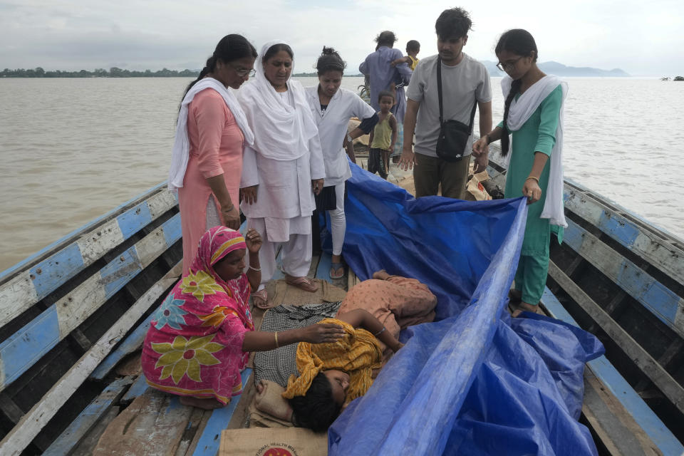 Jahanara Khatoon, de 25 años y que está al final de su embarazo, yace dolorida al inicio del parto, mientras personal médico sostiene una carpa para cubrirla sobre el río Brahmaputra, en el estado nororiental indio de Assam, el miércoles 3 de julio de 2024. (AP Foto/Anupam Nath)