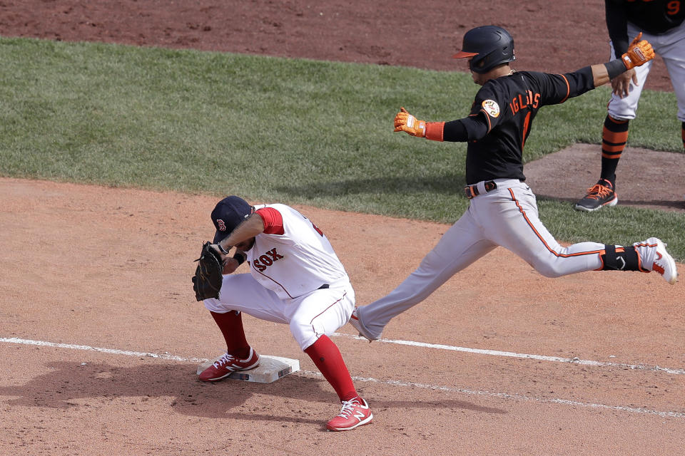 Baltimore Orioles' Jose Iglesias, top, is out at first as Boston Red Sox's Michael Chavis, left, keeps his foot on the base during the eighth inning of a baseball game, Sunday, July 26, 2020, in Boston. The Orioles won 7-4. (AP Photo/Steven Senne)