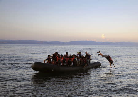 A Syrian refugee dives off an overcrowded dinghy whille approaching a beach on the Greek island of Lesbos, after crossing part of the Aegean Sea from Turkey, September 25, 2015. REUTERS/Yannis Behrakis