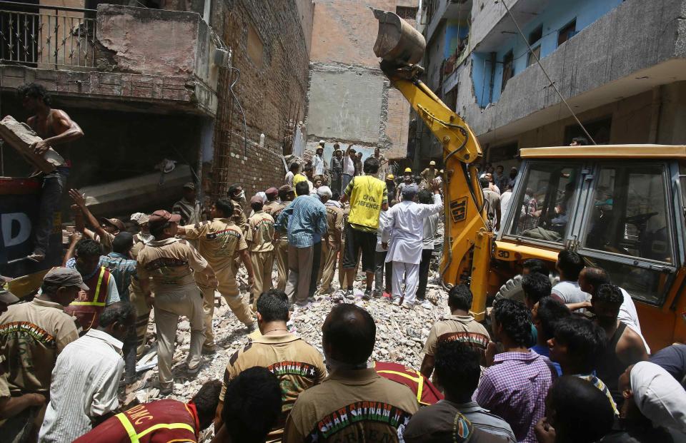 Rescue workers and volunteers stand at the site of a collapsed building in New Delhi