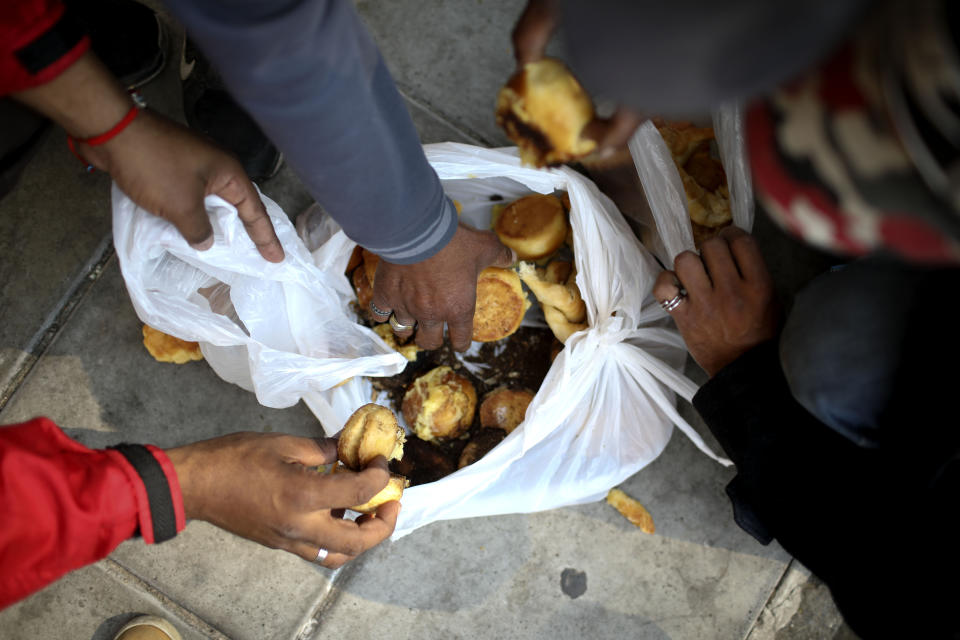 Personas sin hogar buscan pan en una bolsa donada por una panadería en Buenos Aires, Argentina, el lunes 30 de septiembre de 2019. (AP Foto / Natacha Pisarenko)