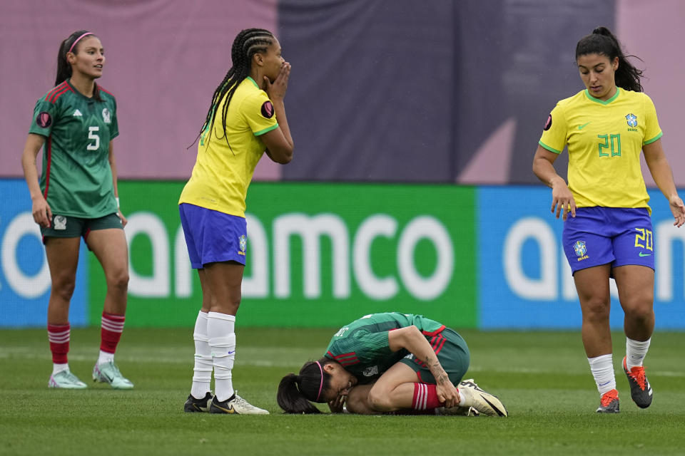 Brazil's Ary Borges, second from left, reacts after fouling Mexico's Lizbeth Ovalle, below, as Brazil's Duda, right, and Mexico's Karen Luna, left, look on during the first half of a CONCACAF Gold Cup women's soccer tournament semifinal match, Wednesday, March 6, 2024, in San Diego. (AP Photo/Gregory Bull)