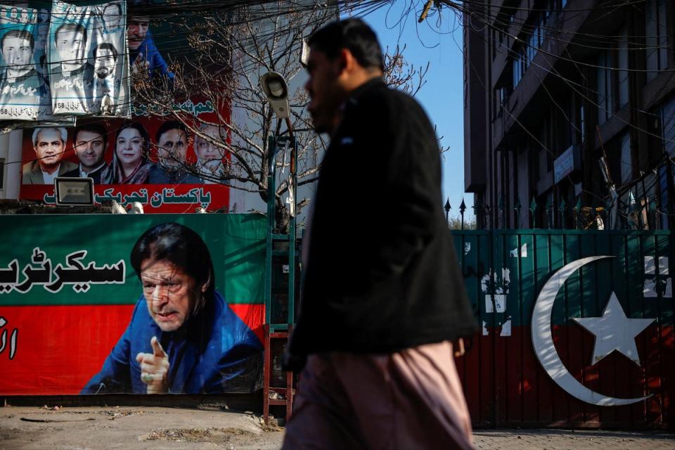 People walk past a banner with a picture of Pakistan’s former prime Minister Imran Khan outside the Pakistan Tehreek-e-Insaf (PTI) offices in Lahore a day after the general election on February 9, 2024 (REUTERS)