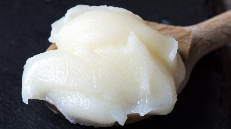 a wooden spoonful of lard on a black background