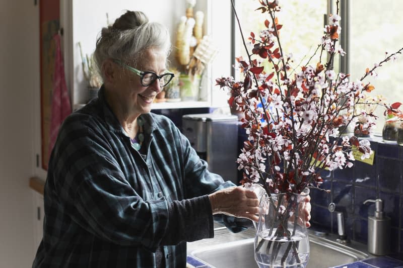 Joan puts flowers in a vase.