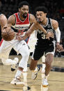 Washington Wizards' Spencer Dinwiddie (26) tangles with San Antonio Spurs' Tre Jones during the first half of an NBA basketball game, Monday, Nov. 29, 2021, in San Antonio. (AP Photo/Darren Abate)