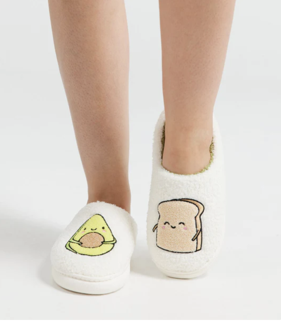 A pair of avocado and toast themed cosy slippers on someone's feet