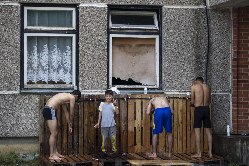 Migrants from Iraq bath at the refugee camp in the village of Verebiejai, some 145km (99,1 miles) south from Vilnius, Lithuania, Sunday, July 11, 2021. Migrants at the school in the village of Verebiejai, about 140 kilometers (87 miles) from Vilnius, haven't been allowed to leave the premises and are under close police surveillance. Some have tested positive for COVID-19 and have been isolated in the building. (AP Photo/Mindaugas Kulbis)