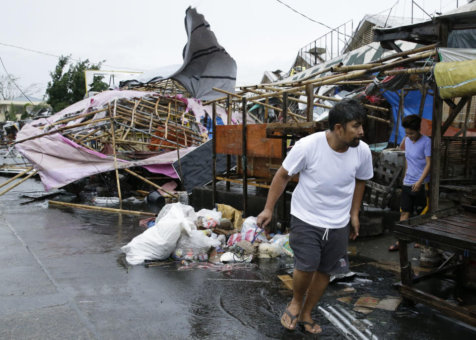 A resident walks past damaged stalls at a public market as Typhoon Mangkhut barreled across Tuguegarao city in Cagayan province, northeastern Philippines on Saturday, Sept. 15, 2018. The typhoon slammed into the Philippines northeastern coast early Saturday, it's ferocious winds and blinding rain ripping off tin roof sheets and knocking out power, and plowed through the agricultural region at the start of the onslaught. (AP Photo/Aaron Favila)