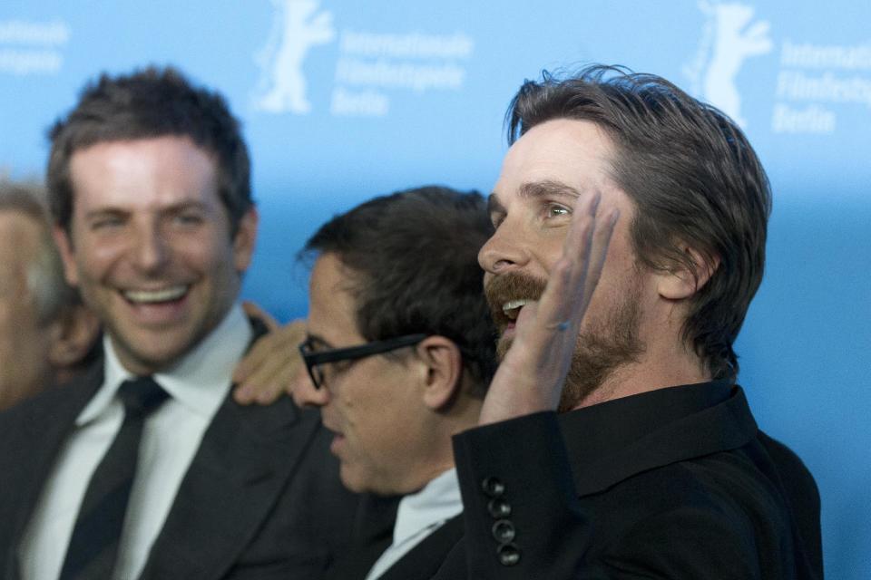 Actor Christian Bale, right, waves at photographers during the photo call for the film American Hustle during the International Film Festival Berlinale, in Berlin, Friday, Feb. 7, 2014. (AP Photo/Axel Schmidt)