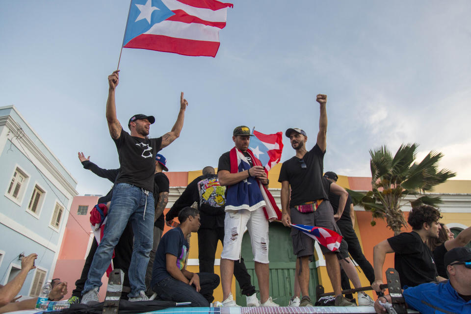 Singer Ricky Martin, left, waves the Puerto Rican flag during march against governor Ricardo Rosello, in San Juan, Puerto Rico, Wednesday, July 17, 2019. Protesters are demanding Rossello step down for his involvement in a private chat in which he used profanities to describe an ex-New York City councilwoman and a federal control board overseeing the island's finance. (AP Photo/Dennis M. Rivera Pichardo)
