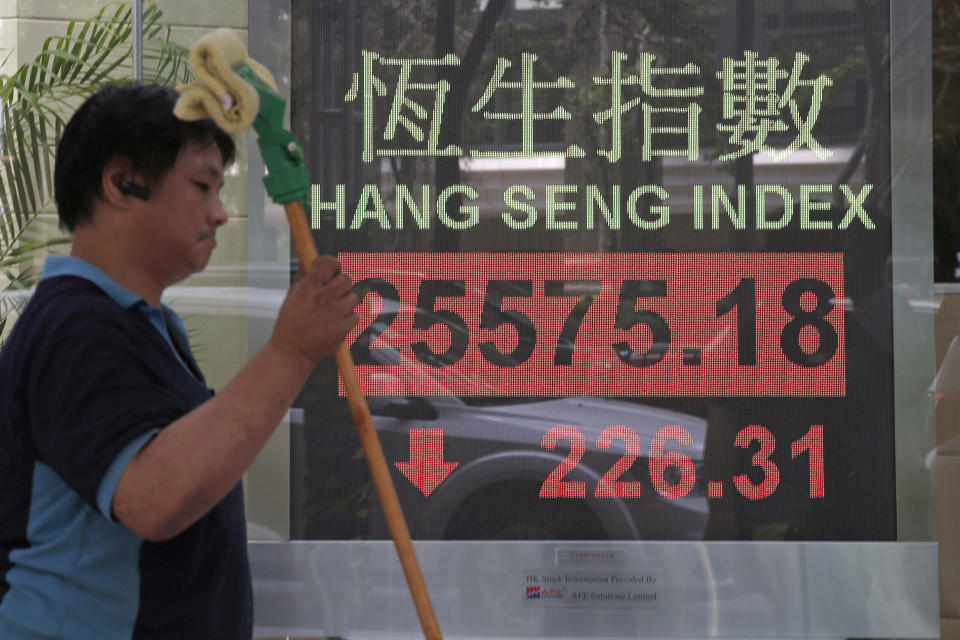 A worker walks past an electronic board showing Hong Kong share index outside a bank In Hong Kong, Monday, Oct. 15, 2018. Asian stocks slipped Monday, as investor worries continued about global trade tensions and prospects for economic growth. (AP Photo/Kin Cheung)