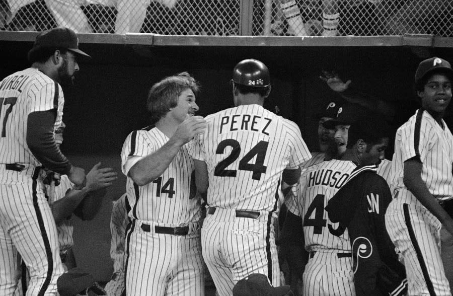 Philadelphia Phillies Pete Rose greets teammate Tony Perez in the dugout after Perez scored on a double by Garry Maddox in the fifth inning of play against the Pittsburgh Pirates at Veterans Stadium in Philadelphia, Aug. 9, 1983. (AP Photo/Peter Morgan)