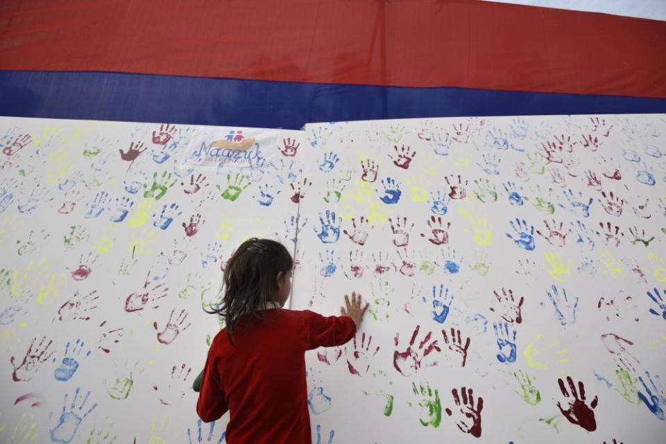 A girl adds her handprint to an art installation during an awareness campaign for missing children.