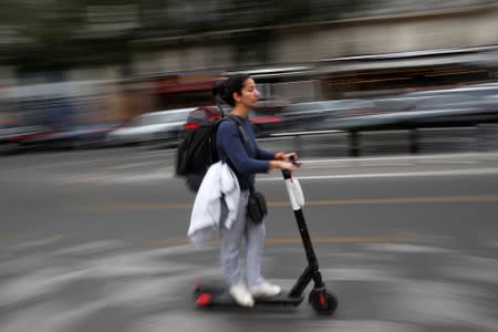 A woman rides a dock-free electric scooter in a street of Paris during a strike by all unions of the Paris transport network (RATP) against pension reform plans in Paris