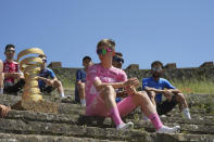 Slovenia's Tadej Pogacar, right, wearing the pink jersey of the race overall leader, sits by The Giro d'Italia trophy displayed at the archaeological area of Pompeii, Italy, Tuesday, May 14, 2024 ahead of the 10th stage of the Giro d'Italia, Tour of Italy cycling race from Pompei to Cusano Mutri. (Gian Mattia D'Alberto/LaPresse via AP)
