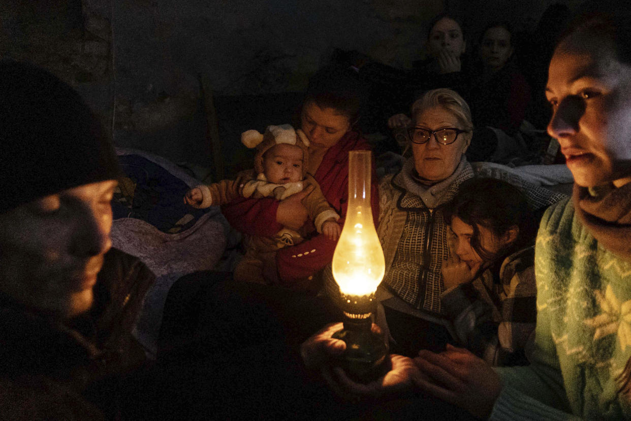 People sit around an oil lamp in a bomb shelter in Mariupol. 