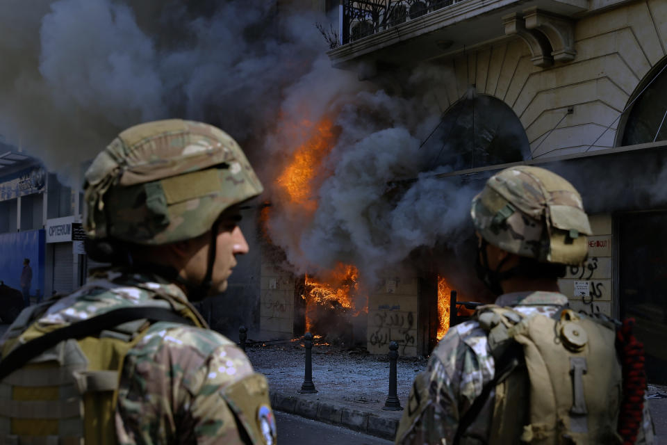 FILE - Lebanese army soldiers stand guard in front of a branch of the Credit Libanais Bank that was set on fire by anti-government protesters, in the northern city of Tripoli, Lebanon, April 28, 2020. Lebanon's once burgeoning banking sector has been hard hit by the country's historic economic meltdown, suffering staggering losses worth tens of billions of dollars and leaving the future of the small nation's lenders unknown between closures and mergers. (AP Photo/Bilal Hussein, File)