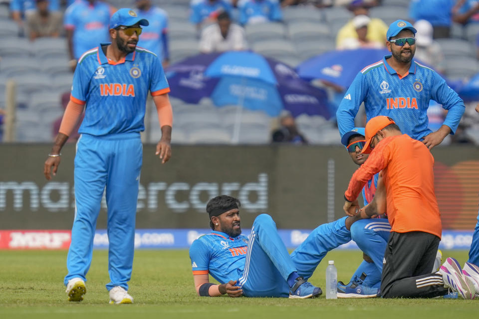 Team physio attends to India's Hardik Pandya, second left, after sustaining an injury during the ICC Men's Cricket World Cup match between India and Bangladesh in Pune, India, Thursday, Oct. 19, 2023. (AP Photo/ Rafiq Maqbool)