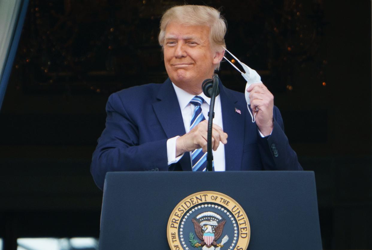 Donald Trump takes his mask off before speaking from the South Portico of the White House in Washington, DC during a rally on 10 October (AFP via Getty Images)