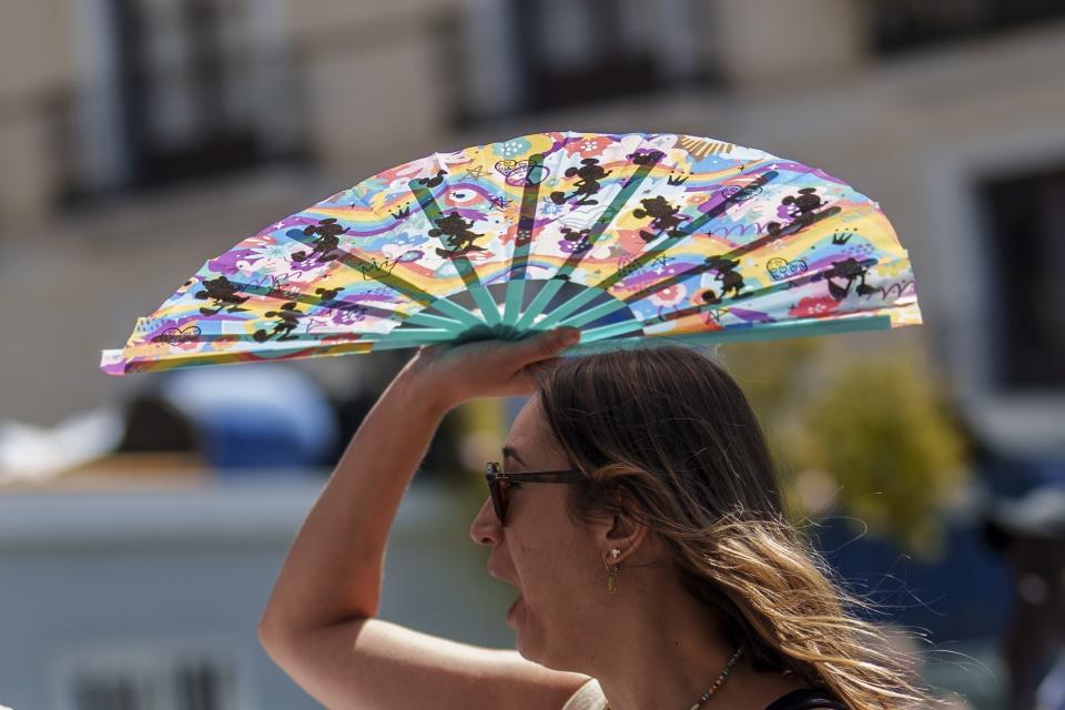 FILE - A woman protects herself with a hand-held fan from the sun in Madrid, Spain, July 10, 2023. The latest calculations from several science agencies Friday, Jan. 12, 2024, all say that global average temperatures for 2023 shattered existing heat records. (AP Photo/Manu Fernandez, File)