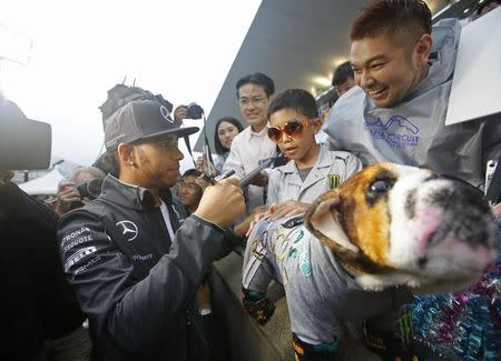 Mercedes Formula One driver Lewis Hamilton of Britain gives his autograph to a young fan who presented Hamilton with a toy of his bulldog Roscoe at the Suzuka circuit in Suzuka, western Japan, October 2, 2014, ahead of Sunday's Japanese F1 Grand Prix. REUTERS/Toru Hanai