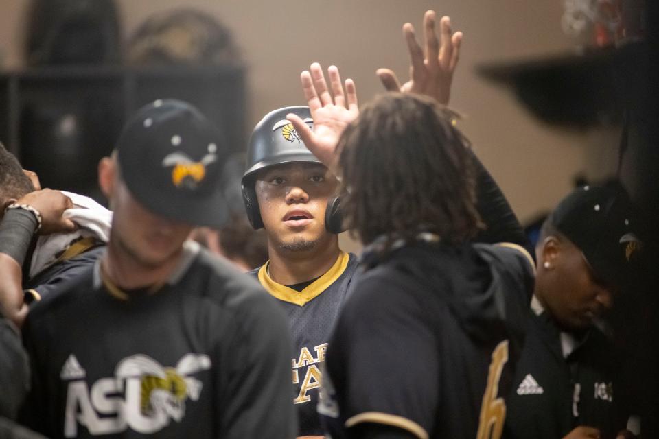 Alabama State outfielder Angel Jimenez (21) gets high-fives after scoring against Florida A&M during an NCAA baseball game on Friday, March 18, 2022, in Montgomery, Ala. (AP Photo/Vasha Hunt)