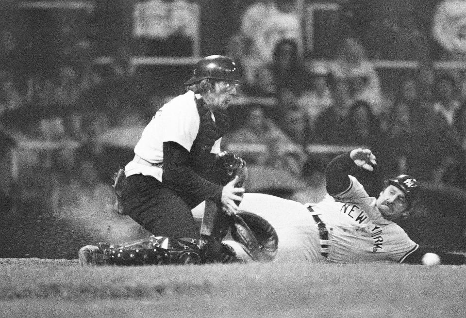 New York Yankees' Thurman Munson slides across home plate to score in the eighth inning as the ball bounces in to Chicago White Sox catcher Brian Downing, Aug. 24, 1977 in Chicago. Munson scored on a Reggie Jackson single to center field.