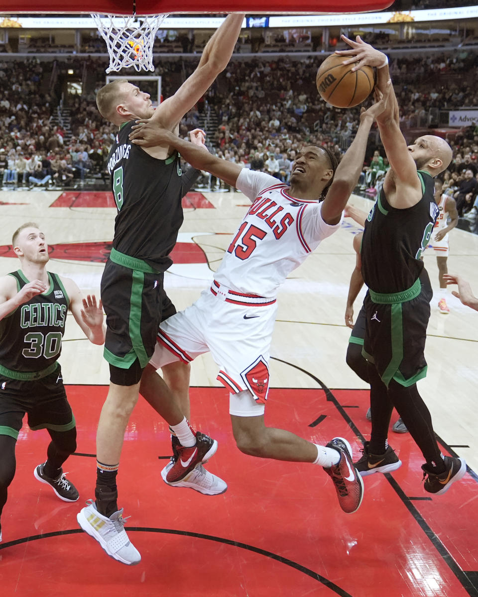 Boston Celtics' Derrick White, right, blocks a shot by Chicago Bulls' Julian Phillips (15) as Celtics' Kristaps Porzingis, second from left, also defends during the first half of an NBA basketball game Thursday, Feb. 22, 2024, in Chicago. (AP Photo/Charles Rex Arbogast)