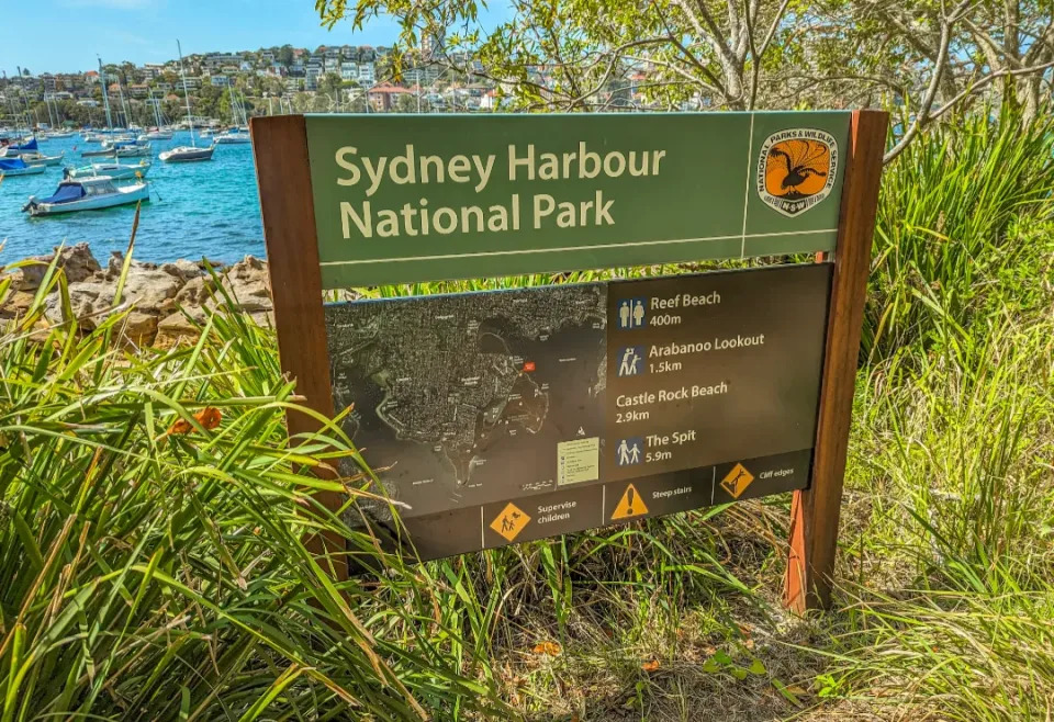 A sign reading Sydney Harbour National Park with the harbour in the background