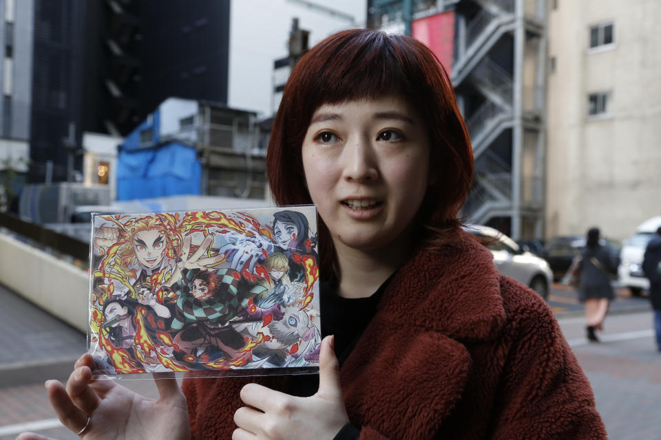 Japanese hairstylist Akina Nasu shows a picture she got when she went to see the film “Demon Slayer,” which has become the nation’s top-grossing film, and opened in Miami to be eligible for the 2021 Academy Awards, in Tokyo Wednesday, March 3, 2021. Nasu and other fans says they identify with the story because of the hardships and fears during the coronavirus pandemic. (AP Photo/Yuri Kageyama)