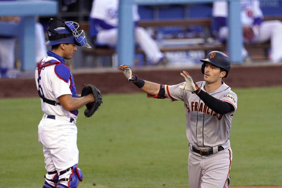 San Francisco Giants' Mike Yastrzemski, right, gestures as he scores after hitting a solo home run, next to Los Angeles Dodgers catcher Austin Barnes during the third inning of a baseball game Saturday, Aug. 8, 2020, in Los Angeles. (AP Photo/Mark J. Terrill)