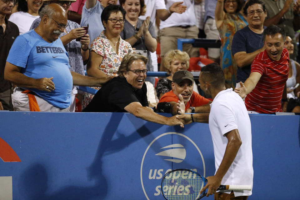 Nick Kyrgios, bottom right, of Australia, celebrates with a spectator in the stands after defeating Stefanos Tsitsipas, of Greece, in a semifinal at the Citi Open tennis tournament, Saturday, Aug. 3, 2019, in Washington. (AP Photo/Patrick Semansky)