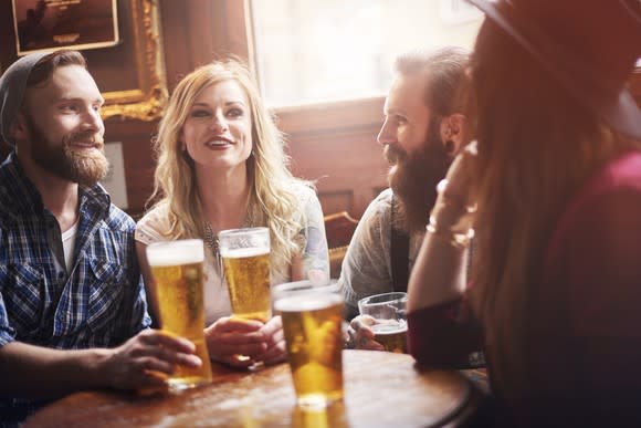 Two men and two women gathered around a table at a bar while drinking beer