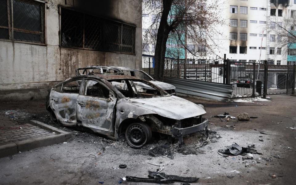 A burned-out car pictured in a street in the aftermath of protests - Tass