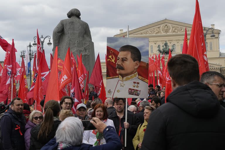 Partidarios del partido comunista se reúnen con banderas rojas y un retrato del líder soviético Josef Stalin para poner flores en la Tumba del Soldado Desconocido fuera del Kremlin antes del Día de la Victoria en Moscú, el lunes 8 de mayo de 2023.