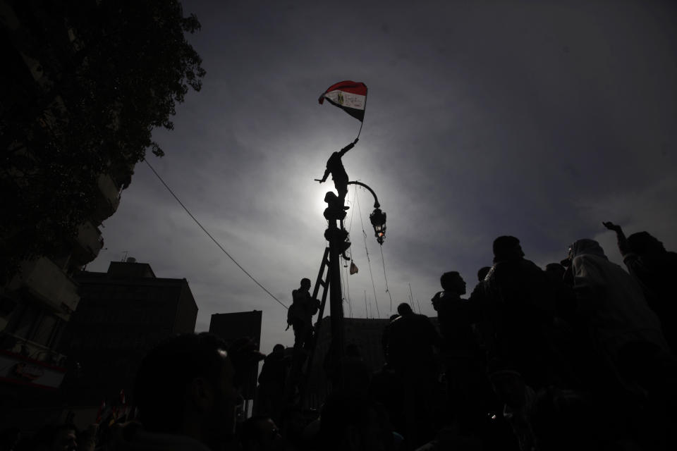 File - In this Friday, Feb. 3, 2012 file photo, an Egyptian protestor climbs a pole waving his national flag during a demonstration in Tahrir Square, Cairo, Egypt. Ten years ago, an uprising in Tunisia opened the way for a wave of popular revolts against authoritarian rulers across the Middle East known as the Arab Spring. For a brief window as leaders fell, it seemed the move toward greater democracy was irreversible. Instead, the region saw its most destructive decade of the modern era. Syria, Yemen, Libya and Iraq have been torn apart by wars, displacement and humanitarian crisis. (AP Photo/Nathalie Bardou, File)