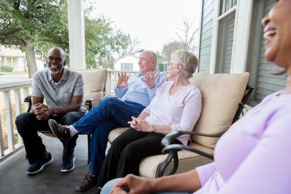 Neighbors chatting on a porch - Getty Images