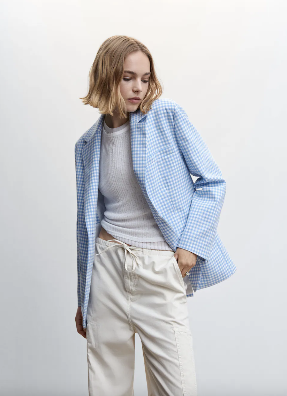 blonde model wearing white pants and blue and white Gingham Blazer (Photo via Mango)